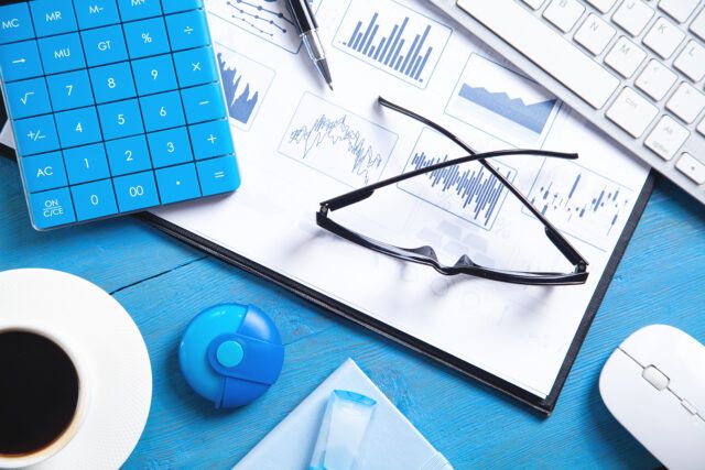 Accounting desk with charts, keyboard, coffee, and financial paperwork.
